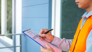 A property inspector takes notes on a checklist.