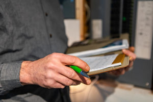A property inspector holds a notebook with an inspection checklist.